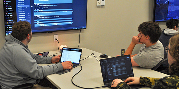 Three people at a table wroting code together